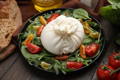 Delicious burrata salad on wooden table, closeup