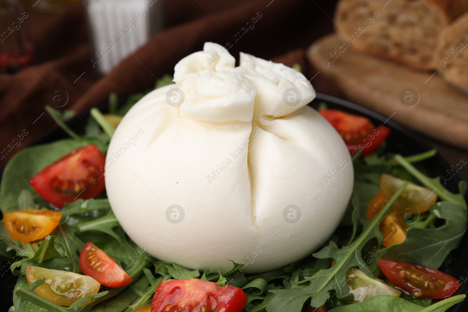 Photo of Fresh delicious burrata salad on table, closeup