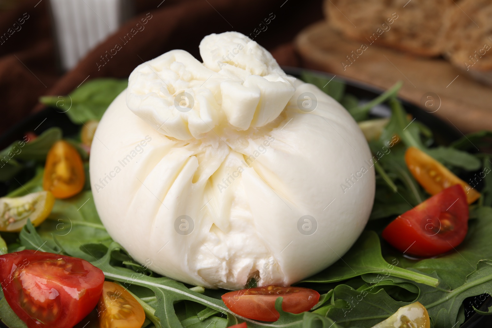 Photo of Fresh delicious burrata salad on table, closeup