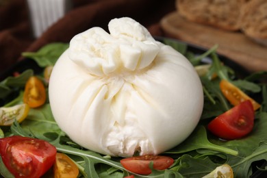 Fresh delicious burrata salad on table, closeup