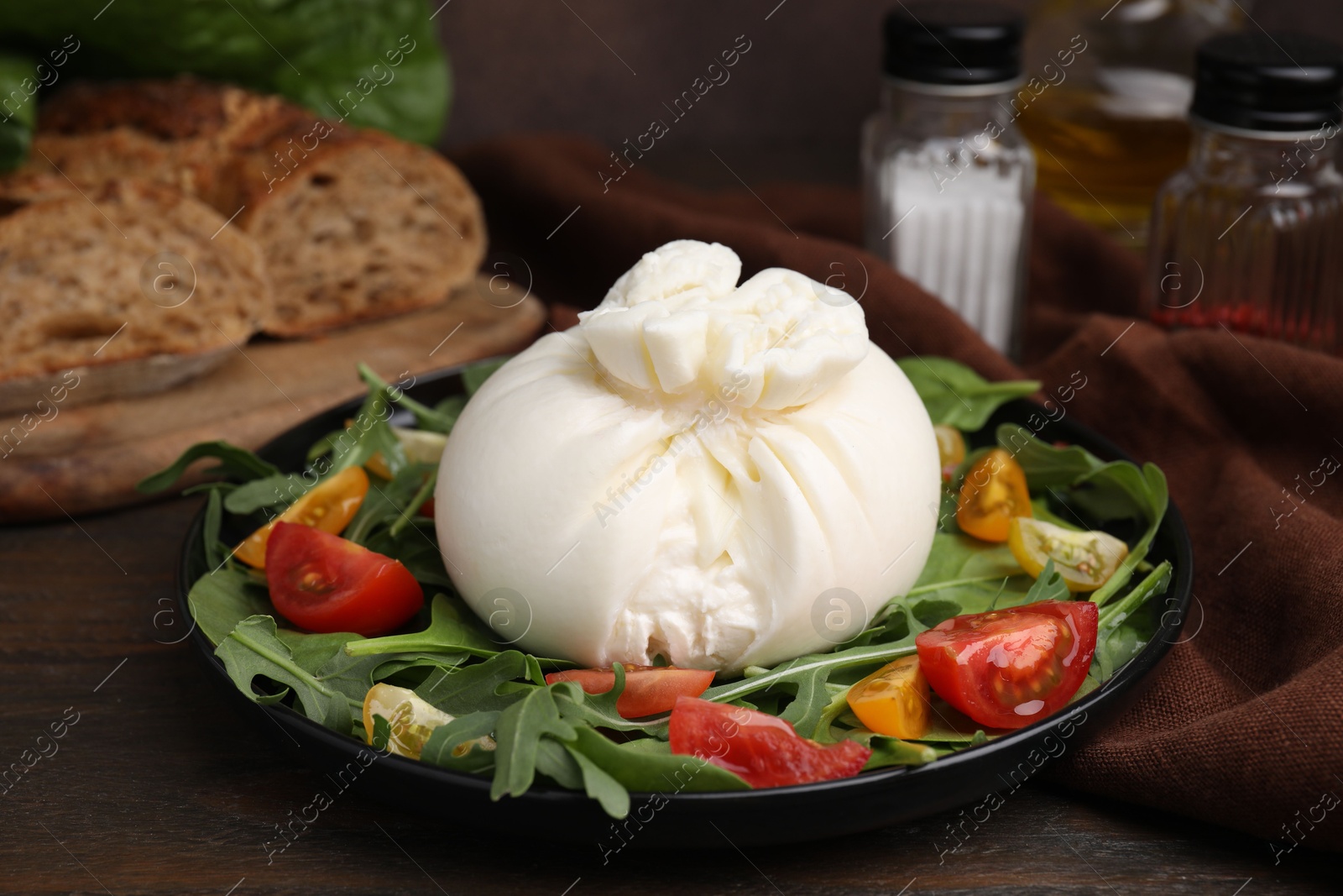 Photo of Delicious burrata salad on wooden table, closeup