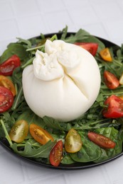 Photo of Delicious burrata salad on white tiled table, closeup