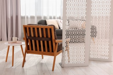 White folding screen, armchair and wooden table in living room