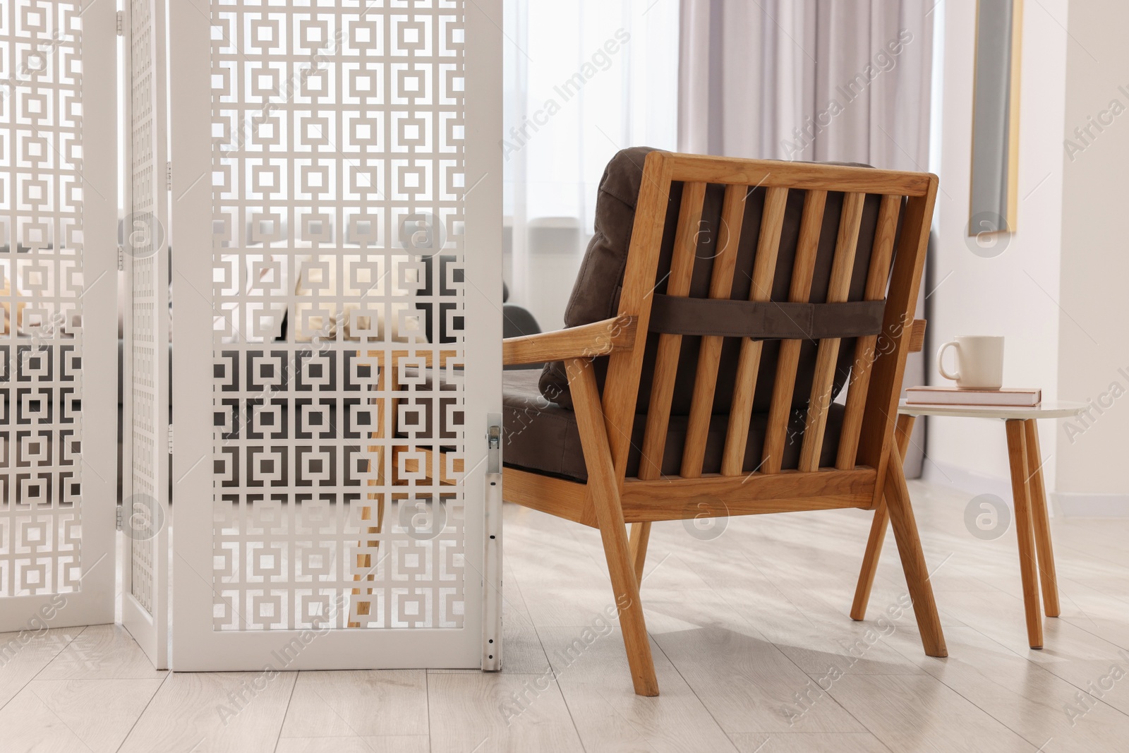 Photo of White folding screen, armchair and wooden table in living room