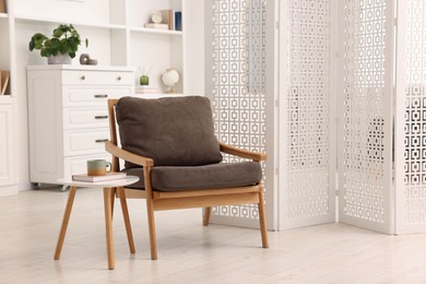 Photo of White folding screen, armchair and wooden table in living room