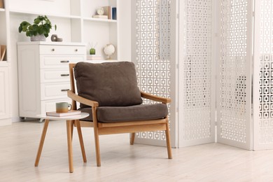 White folding screen, armchair and wooden table in living room