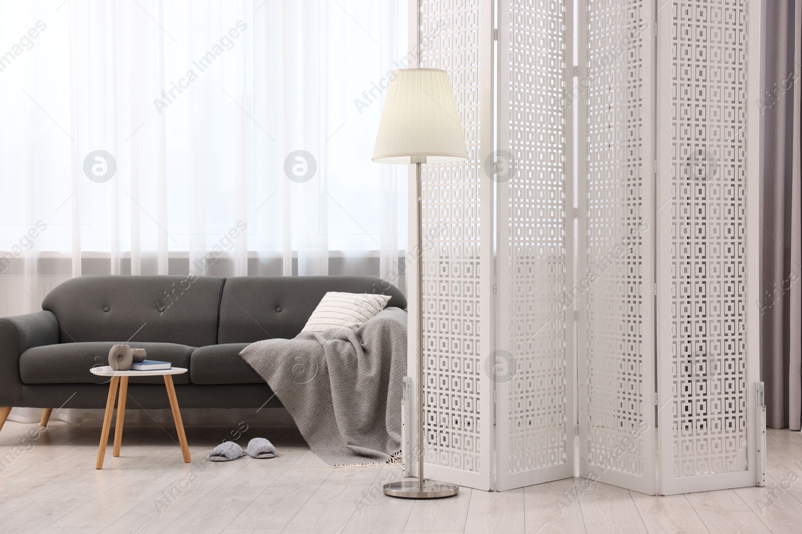 Photo of White folding screen, sofa, side table and lamp in living room