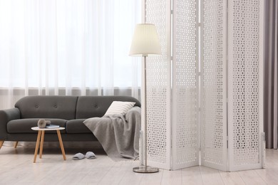 White folding screen, sofa, side table and lamp in living room