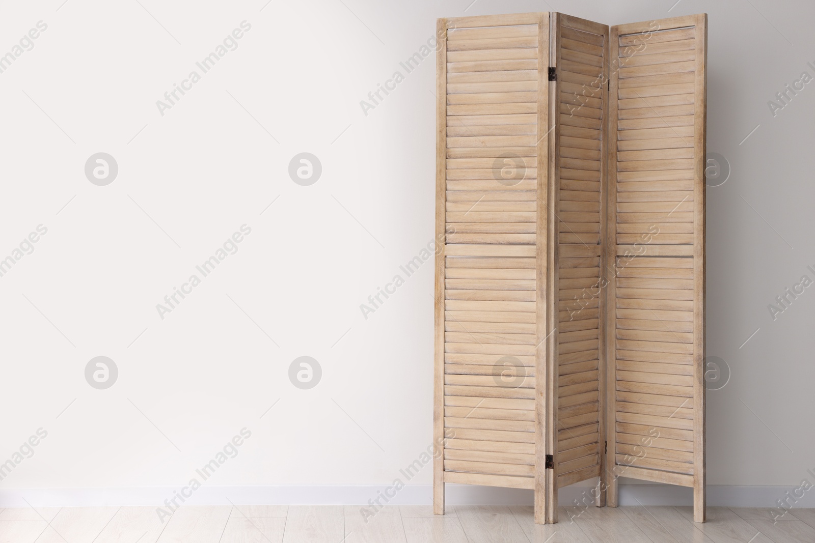 Photo of Wooden folding screen near white wall indoors, space for text