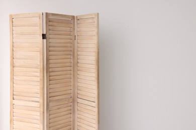 Wooden folding screen near white wall indoors, space for text