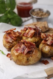 Delicious baked potatoes with bacon on table, closeup