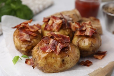 Delicious baked potatoes with bacon on table, closeup