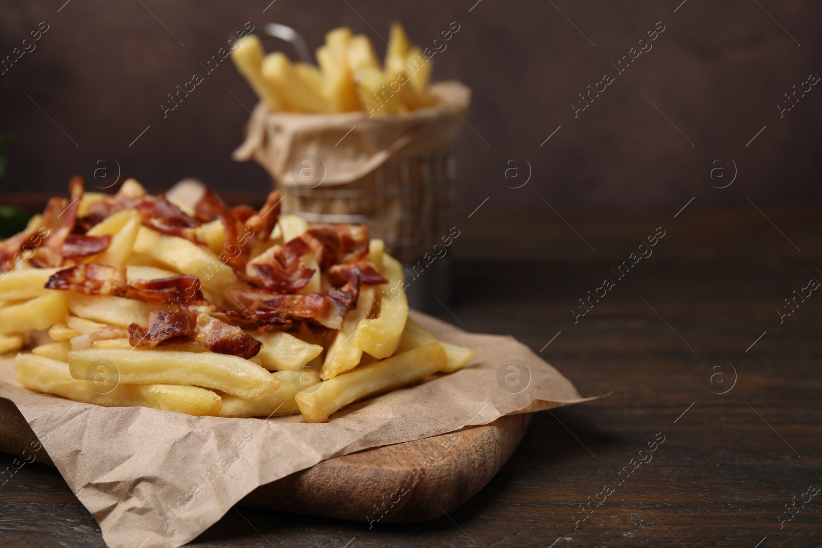 Photo of Delicious French fries with slices of bacon on wooden table, closeup. Space for text