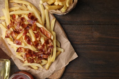 Photo of Delicious French fries with bacon on wooden table, flat lay. Space for text