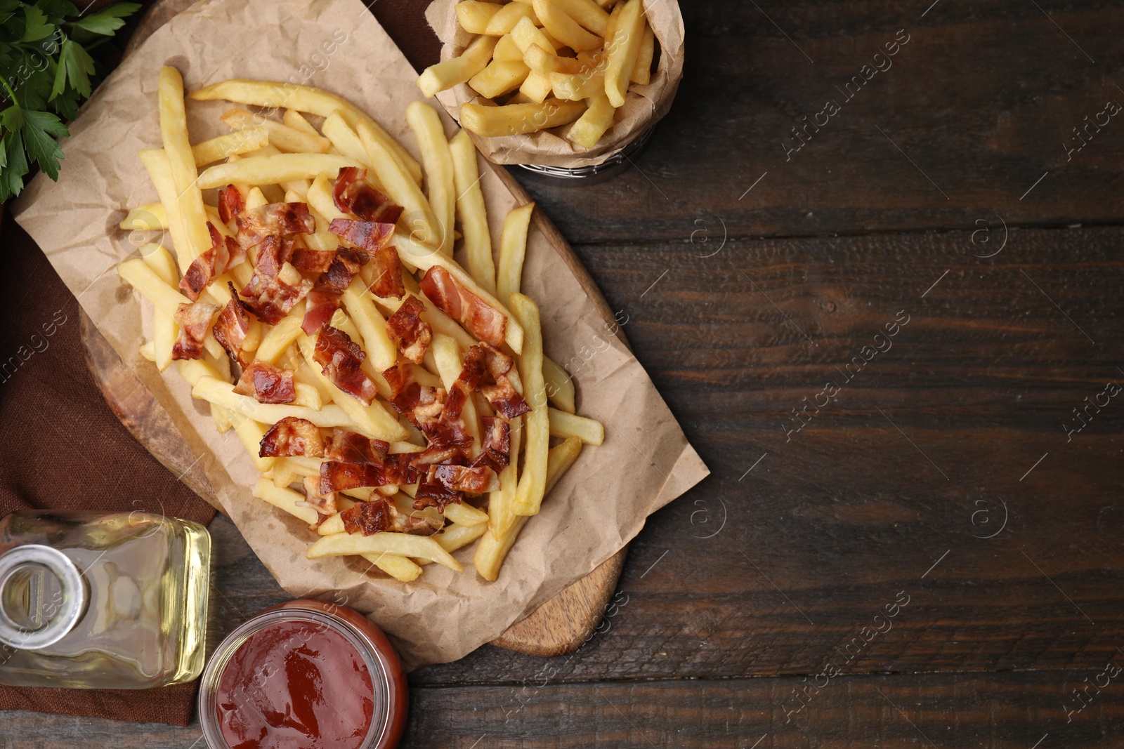 Photo of Delicious French fries with bacon and ketchup on wooden table, flat lay. Space for text