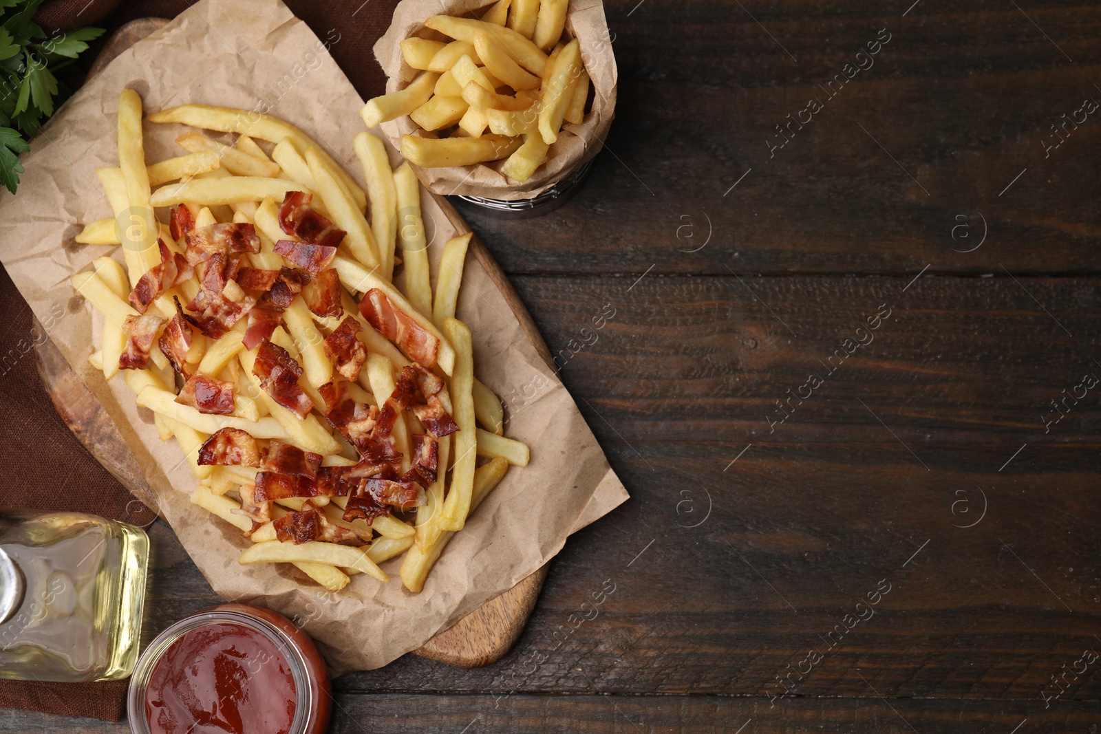 Photo of Delicious French fries with bacon and ketchup on wooden table, flat lay. Space for text