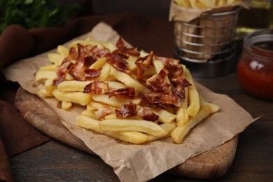 Photo of Delicious French fries with slices of bacon on wooden table, closeup