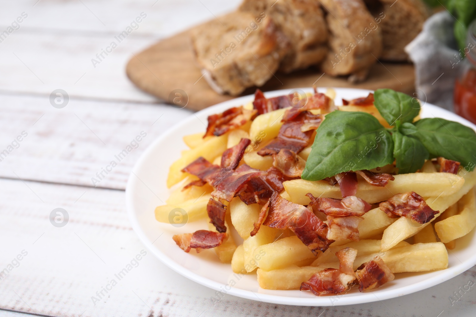 Photo of Delicious French fries with bacon and basil on wooden rustic table, closeup. Space for text