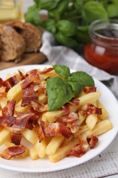 Delicious French fries with slices of bacon and basil on wooden rustic table, closeup