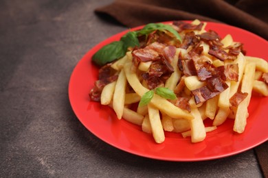 Delicious French fries with bacon and basil on brown background, closeup. Space for text