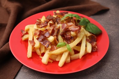 Photo of Delicious French fries with slices of bacon and basil on brown background, closeup