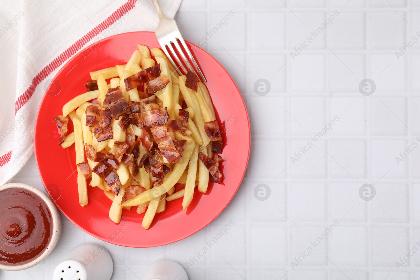 Photo of Delicious French fries with bacon served on white tiled table, flat lay. Space for text