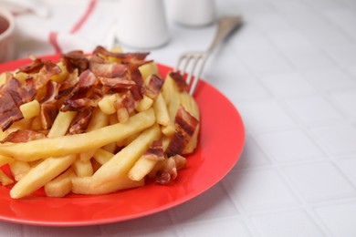 Photo of Delicious French fries with bacon on white tiled table, closeup. Space for text