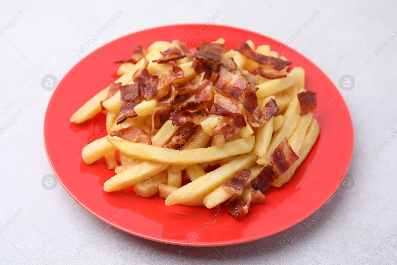 Photo of Delicious French fries with slices of bacon on light background, closeup