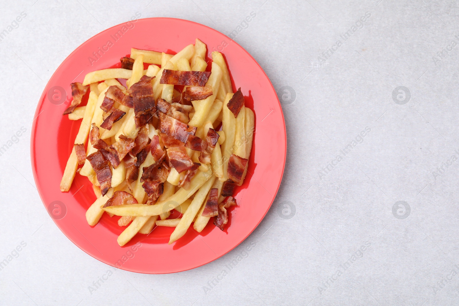 Photo of Delicious French fries with bacon on light background, top view. Space for text