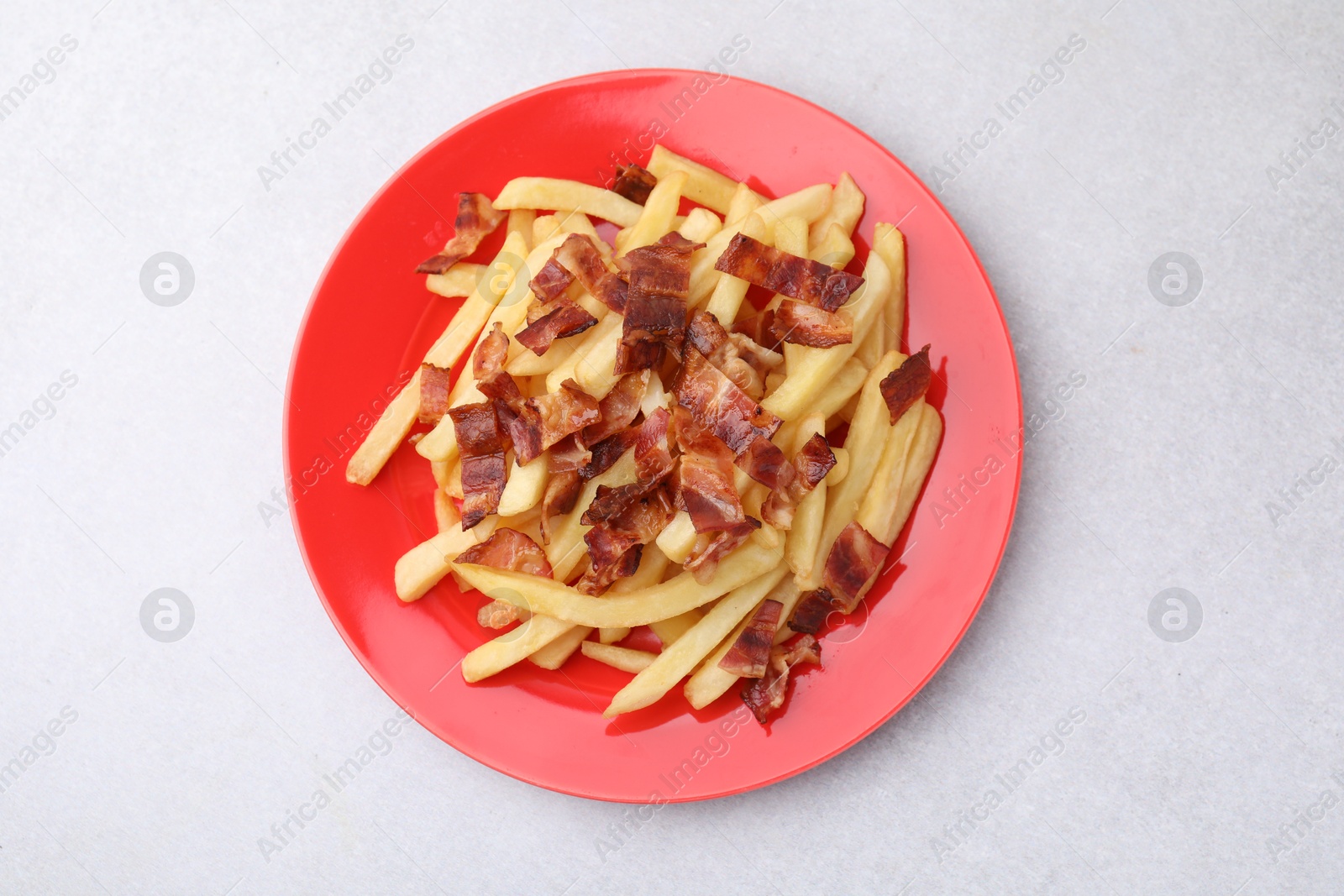 Photo of Delicious French fries with slices of bacon on light background, top view