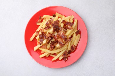 Delicious French fries with slices of bacon on light background, top view