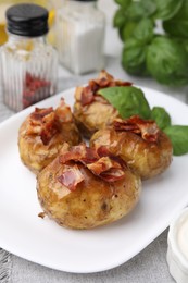 Photo of Delicious baked potatoes with bacon and basil on table, closeup