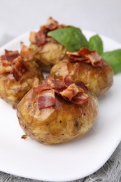 Photo of Delicious baked potatoes with bacon and basil on table, closeup