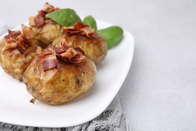 Photo of Delicious baked potatoes with bacon and basil on grey table, closeup. Space for text