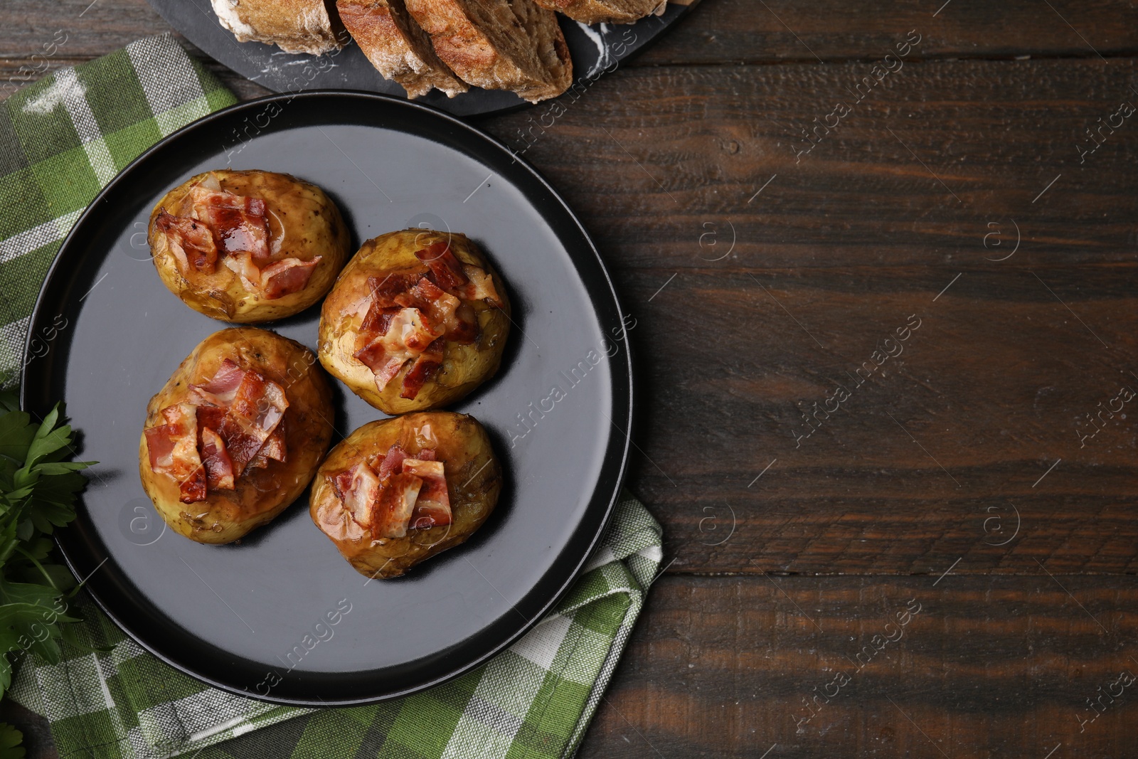 Photo of Delicious baked potatoes with bacon on wooden table, flat lay. Space for text