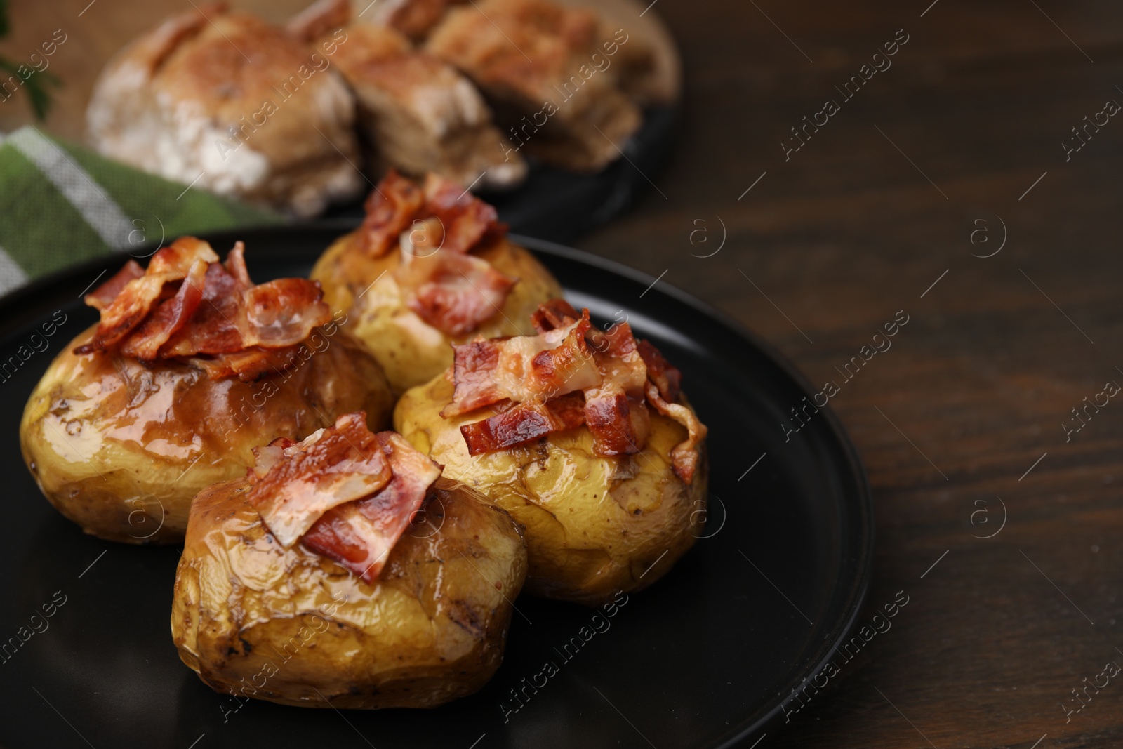 Photo of Delicious baked potatoes with bacon on wooden table, closeup. Space for text