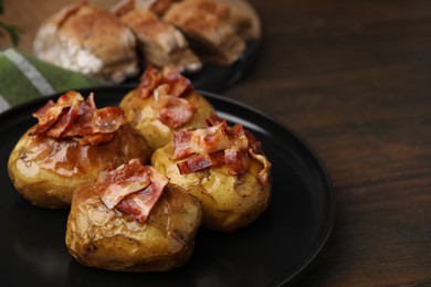 Photo of Delicious baked potatoes with bacon on wooden table, closeup. Space for text