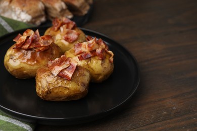 Photo of Delicious baked potatoes with bacon on wooden table, closeup. Space for text