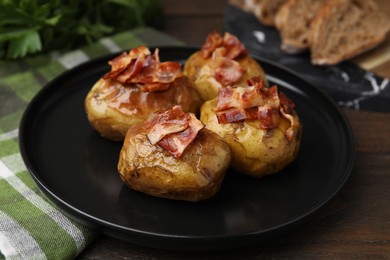 Photo of Delicious baked potatoes with bacon on wooden table, closeup