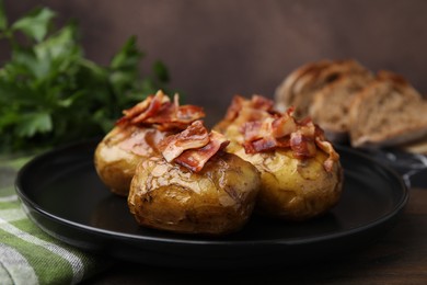 Photo of Delicious baked potatoes with bacon on wooden table, closeup