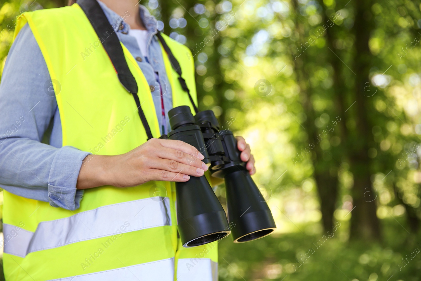 Photo of Forester with binoculars examining plants in forest, closeup. Space for text