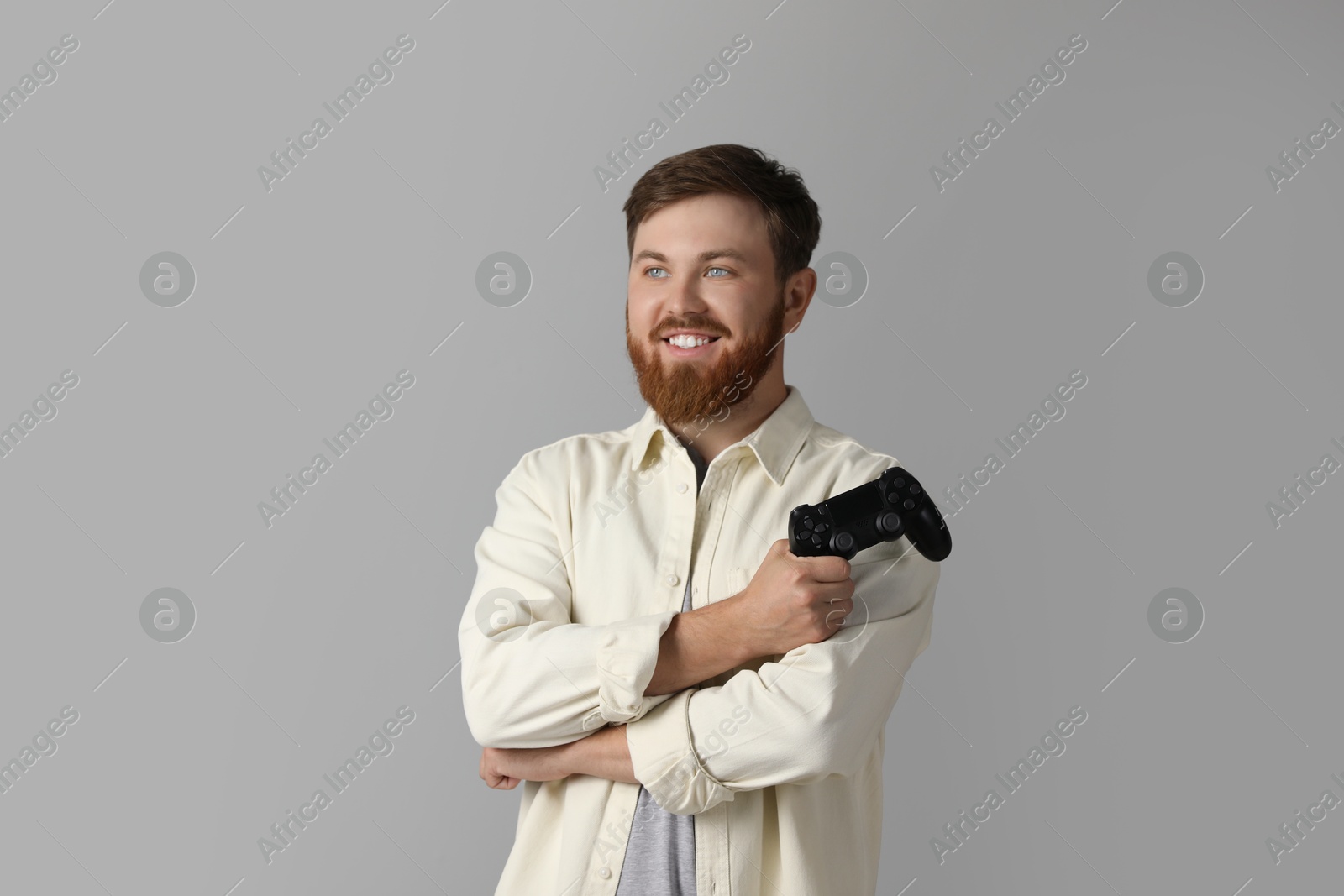 Photo of Smiling man with game controller on grey background