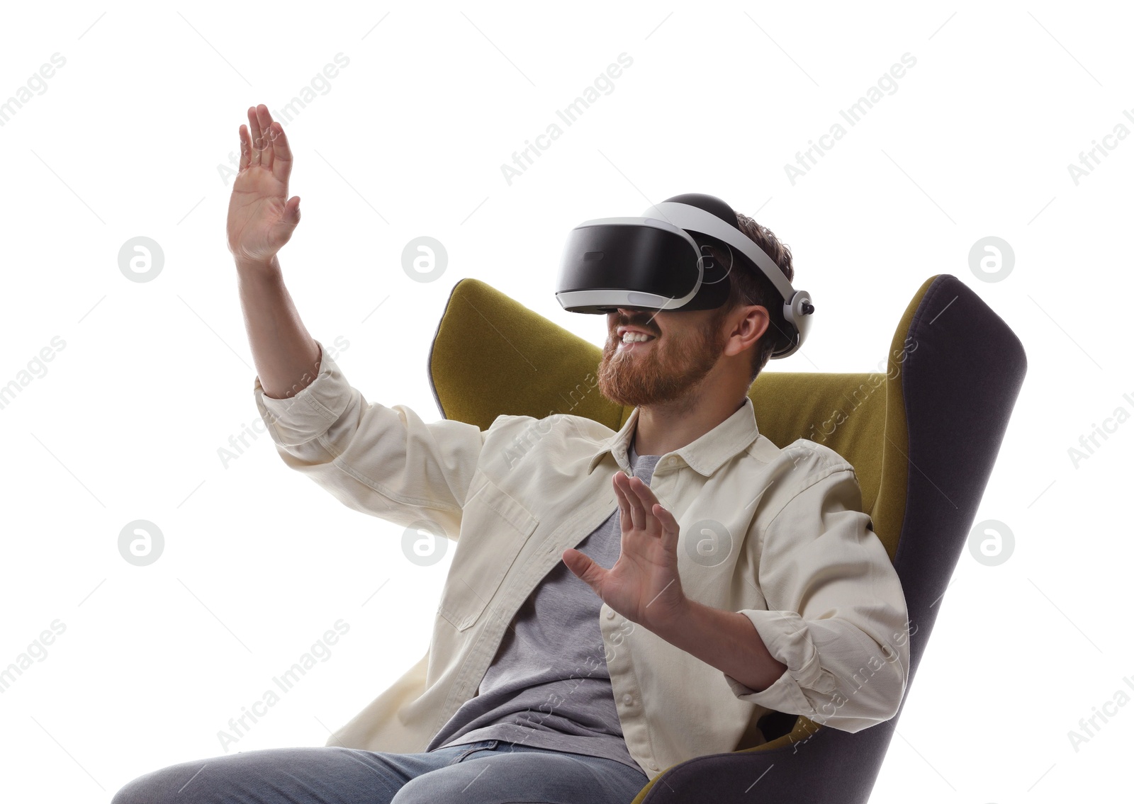 Photo of Smiling man using virtual reality headset while sitting in armchair on white background