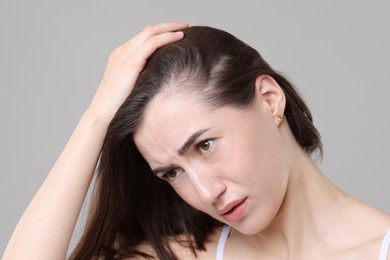 Sad woman with hair loss problem on grey background