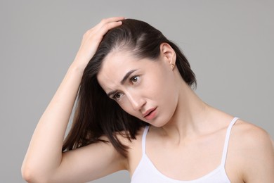 Sad woman with hair loss problem on grey background