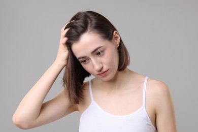 Sad woman with hair loss problem on grey background