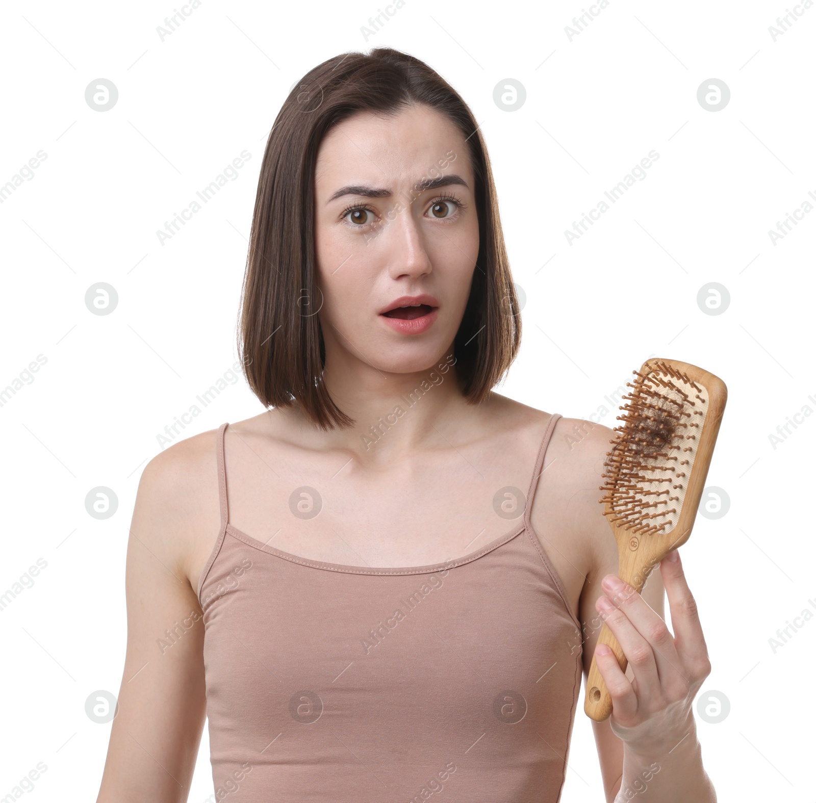 Photo of Emotional woman holding brush with lost hair on white background. Alopecia problem