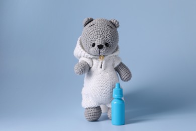 Photo of Toy bear and nasal spray on light blue background