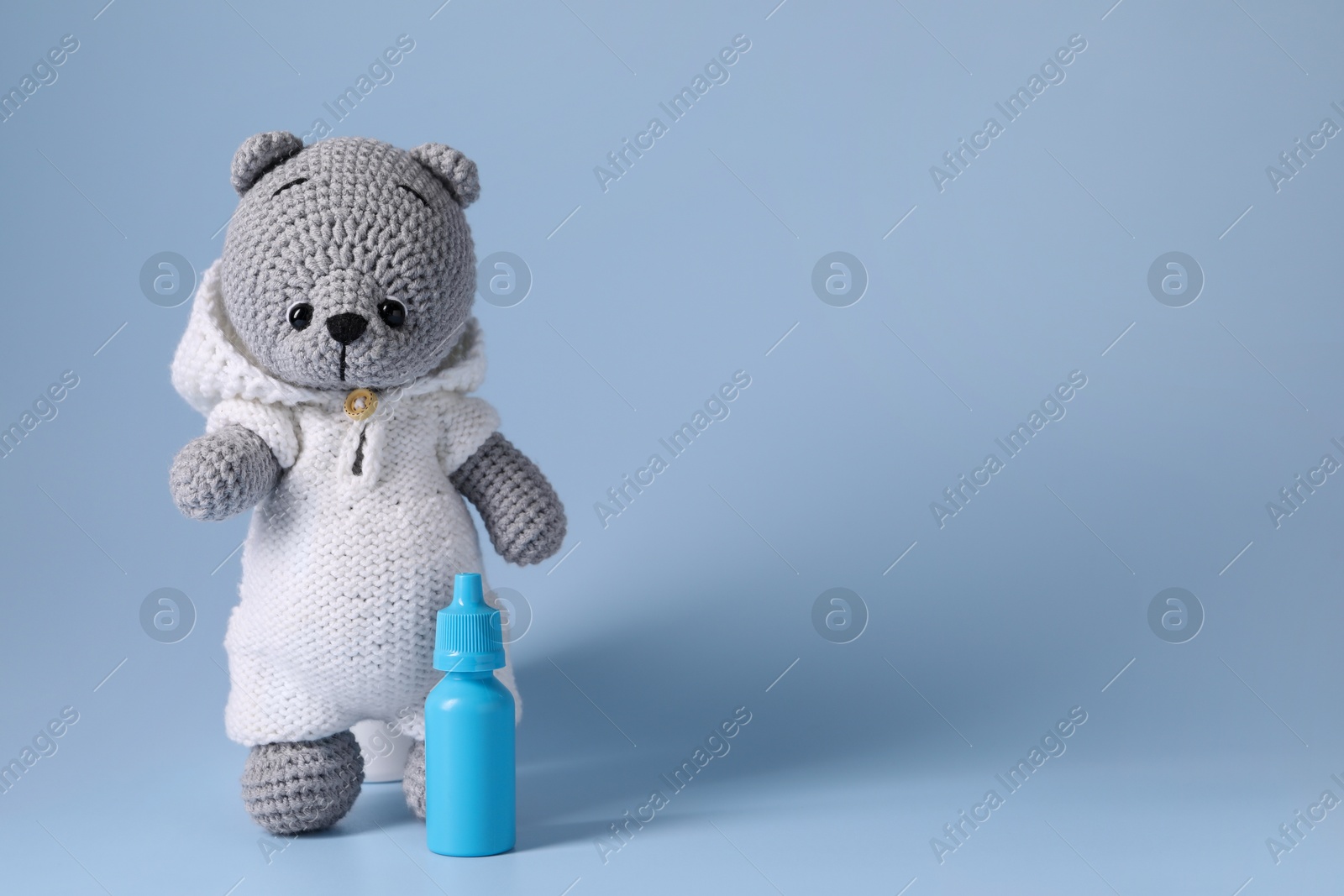 Photo of Toy bear and nasal spray on light blue background, space for text