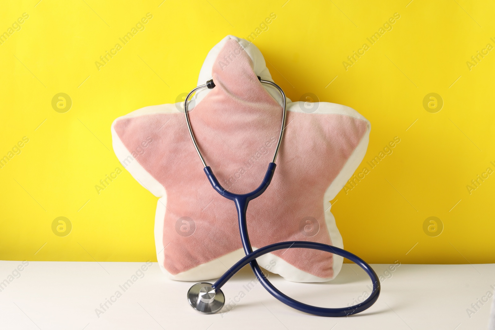 Photo of Star shaped pillow with stethoscope on color background